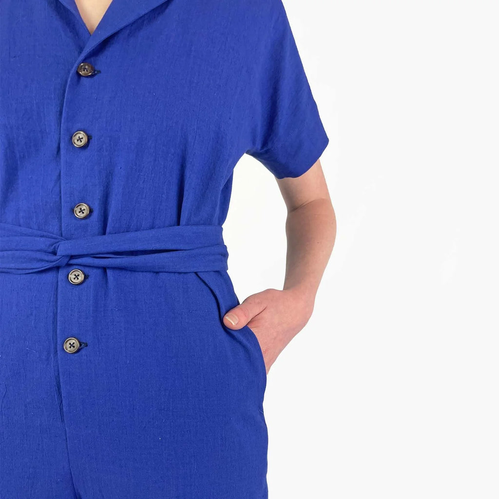 Bumper Jumper sewing pattern — woman wearing a loose-fit blue woven jumper with side pockets, front buttons and roll-up sleeves, detail view