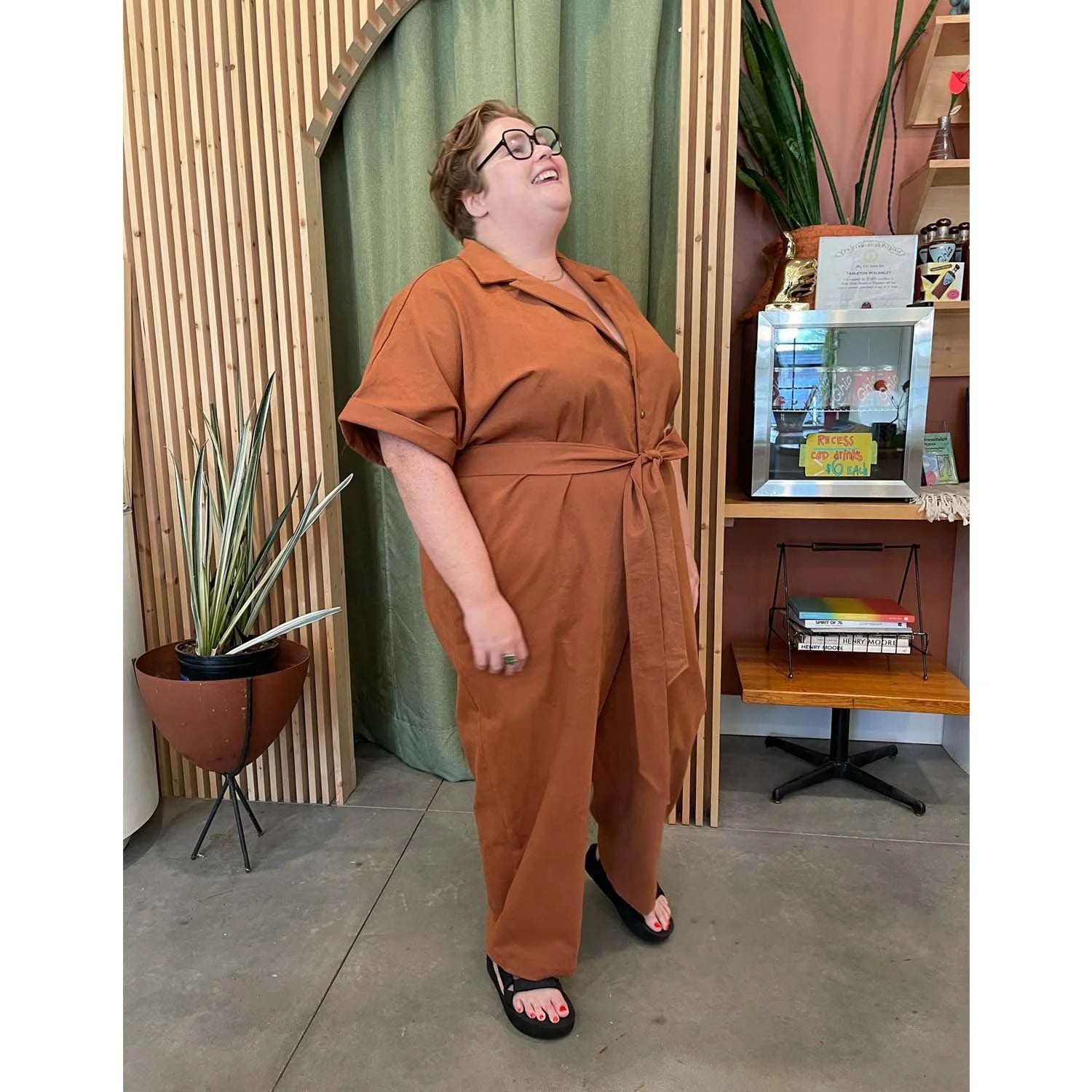 Bumper Jumper sewing pattern — plus size woman wearing a loose-fit orange woven jumper with side pockets, front buttons and roll-up sleeves, side view