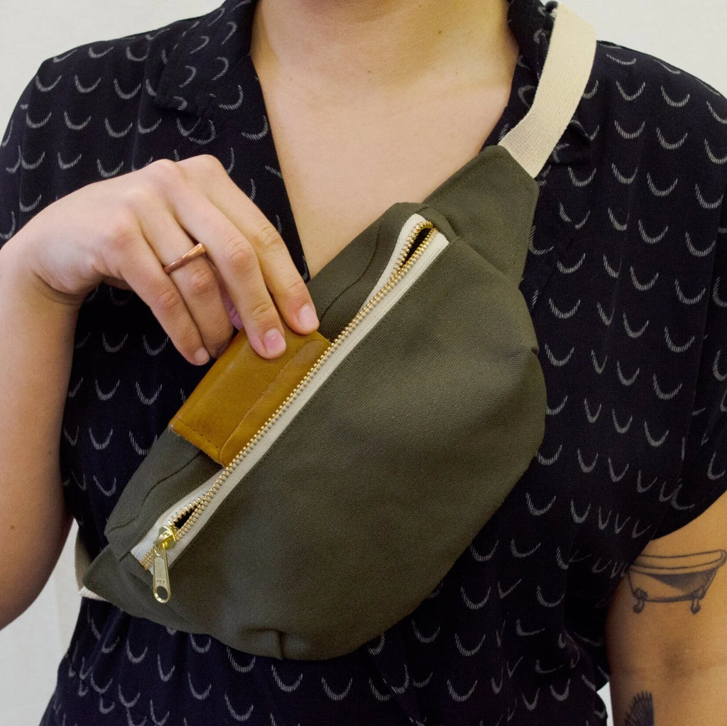 Hip Pack sewing pattern — model wearing olive green over the cross body bag and inserting a wallet, front view