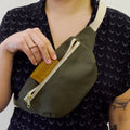 Hip Pack sewing pattern — model wearing olive green over the cross body bag and inserting a wallet, front view