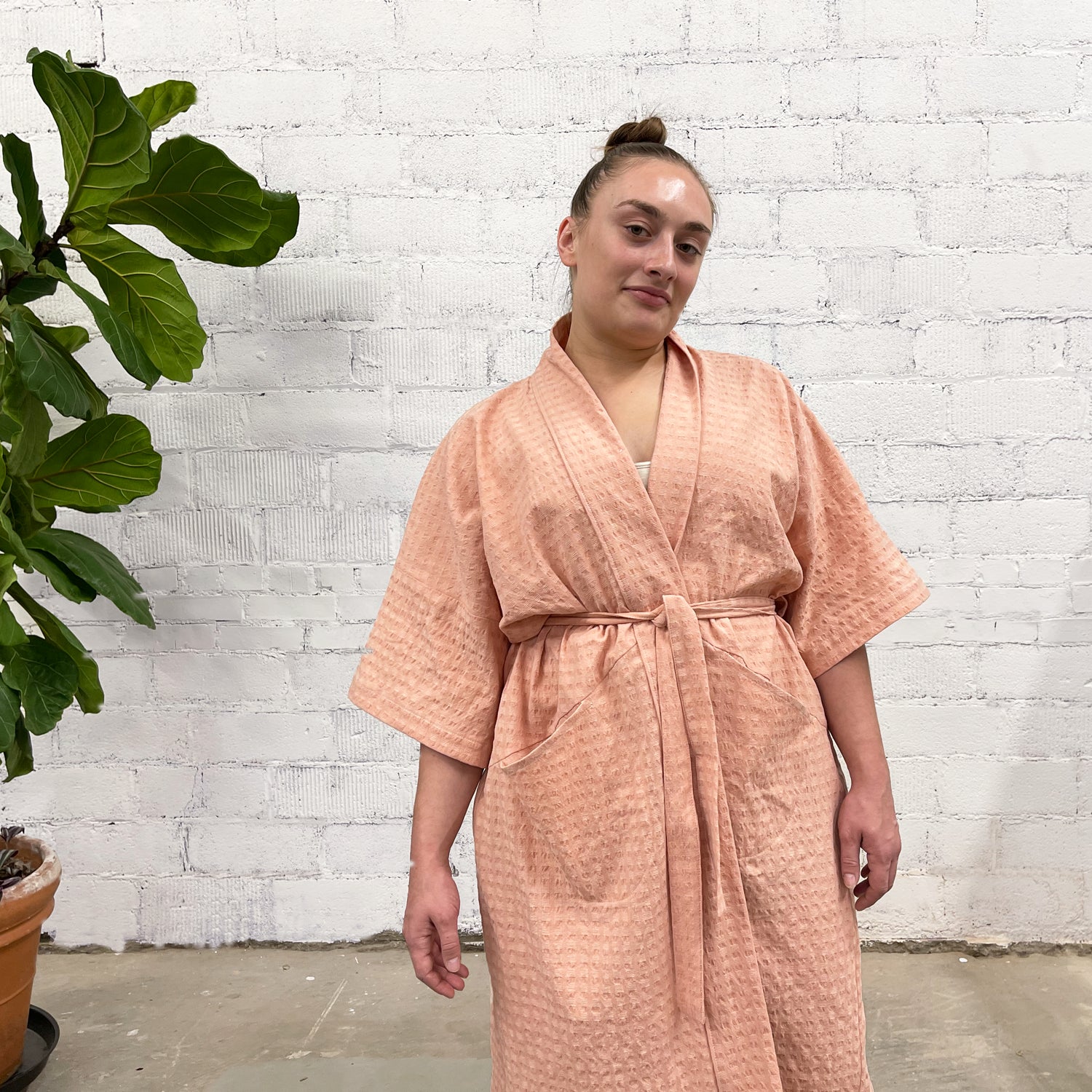 Slow Robe sewing pattern — model wearing knee-length robes with kimono sleeves, tie waist, and patch pockets; pink waffle fabric (left) and pink waffle fabric (right), front close view