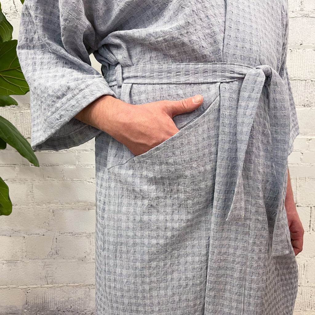 Slow Robe sewing pattern — model wearing knee-length robes with kimono sleeves, tie waist, and patch pockets; blue-grey waffle fabric, pocket detail view