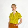 Bumper Blouse sewing pattern —model wearing short sleeved rolled cuff shirt with notched collar and buttoned front in striped yellow and tan fabric, front view