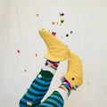Cozy Slipper sewing pattern in yellow with Colorful striped socks and confetti falling