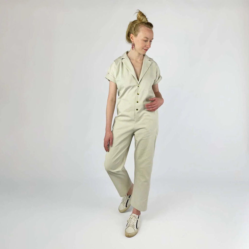 Bumper Bundle sewing pattern — Woman wearing a beige jumpsuit with center front snaps on a plain background - front view