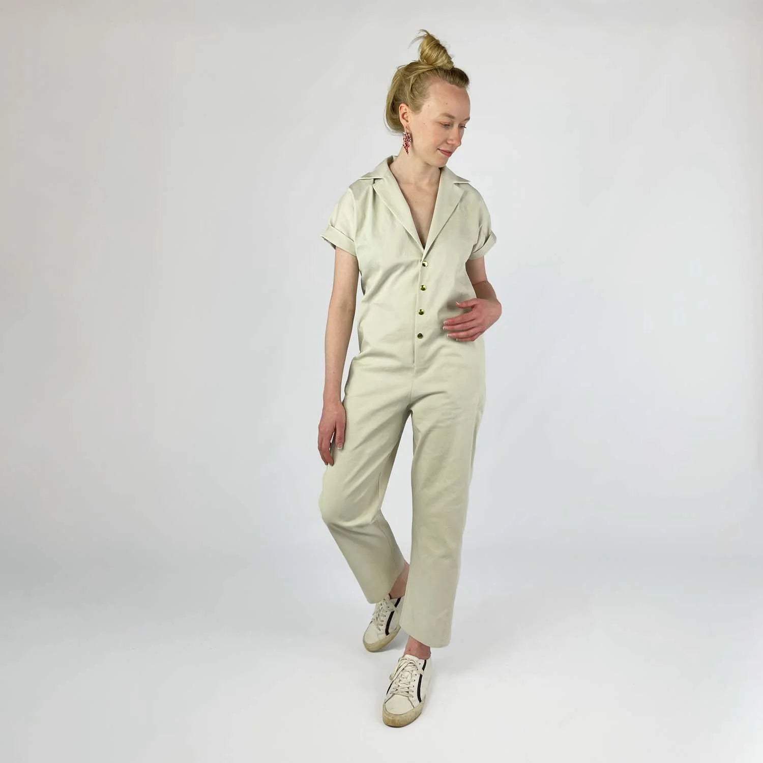 Bumper Bundle sewing pattern — Woman wearing a beige jumpsuit with center front snaps on a plain background - front view