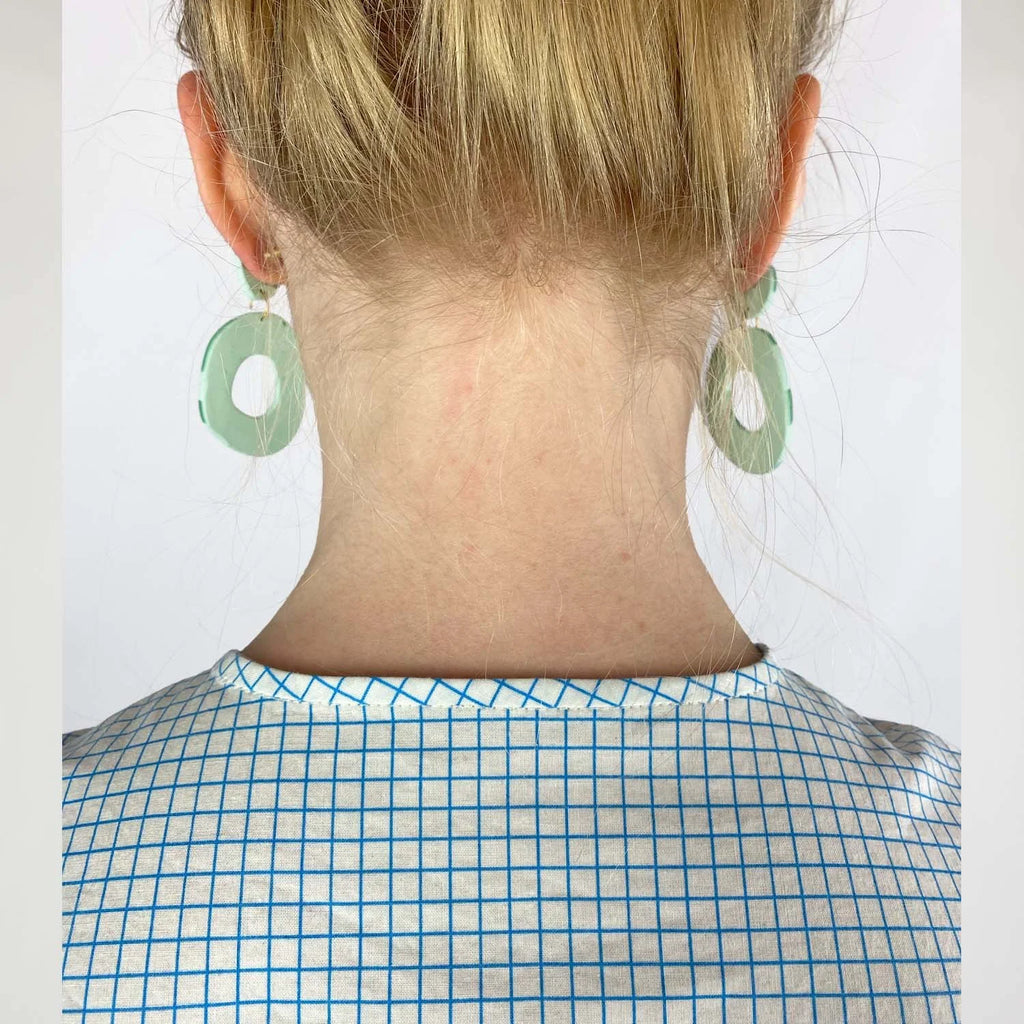 Gable Shirt sewing pattern — model wearing a button-front blouse in a grid paper patterned fabric with long sleeves sleeves and collarless neckline, detail neckline view