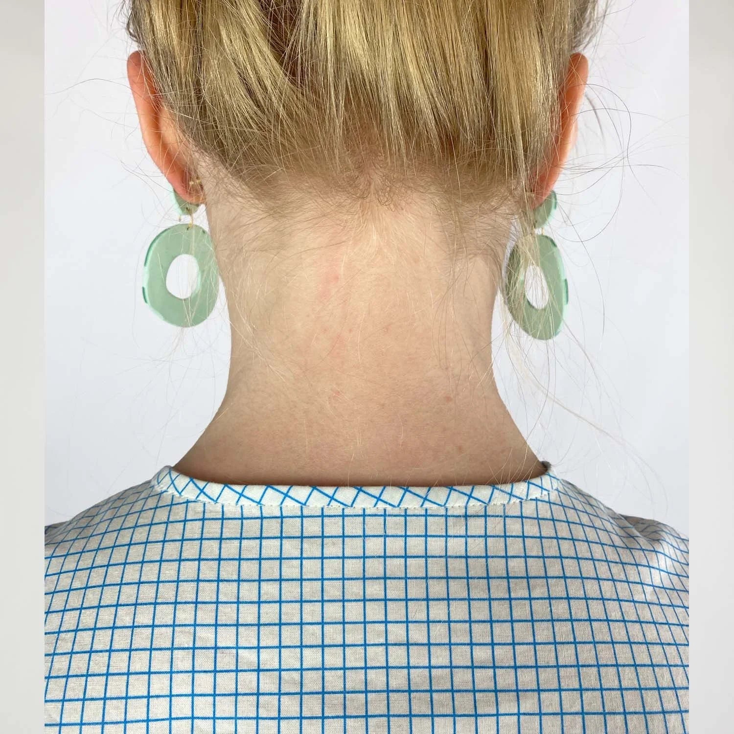 Gable Shirt sewing pattern — model wearing a button-front blouse in a grid paper patterned fabric with long sleeves sleeves and collarless neckline, detail neckline view