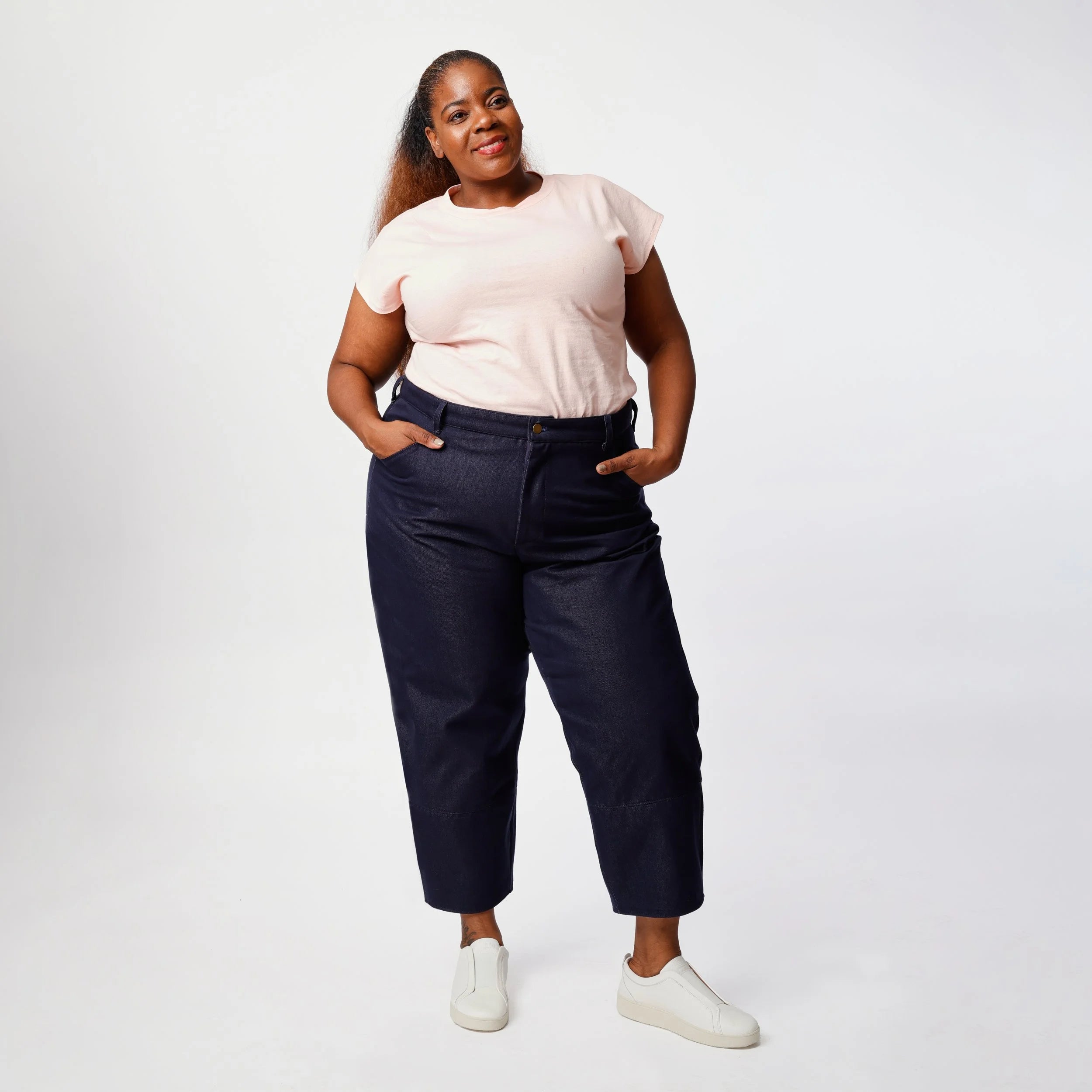 Shop Pant sewing pattern — plus size model wearing high-waisted barrel leg pant in indigo denim twill with front pockets and belt, front view