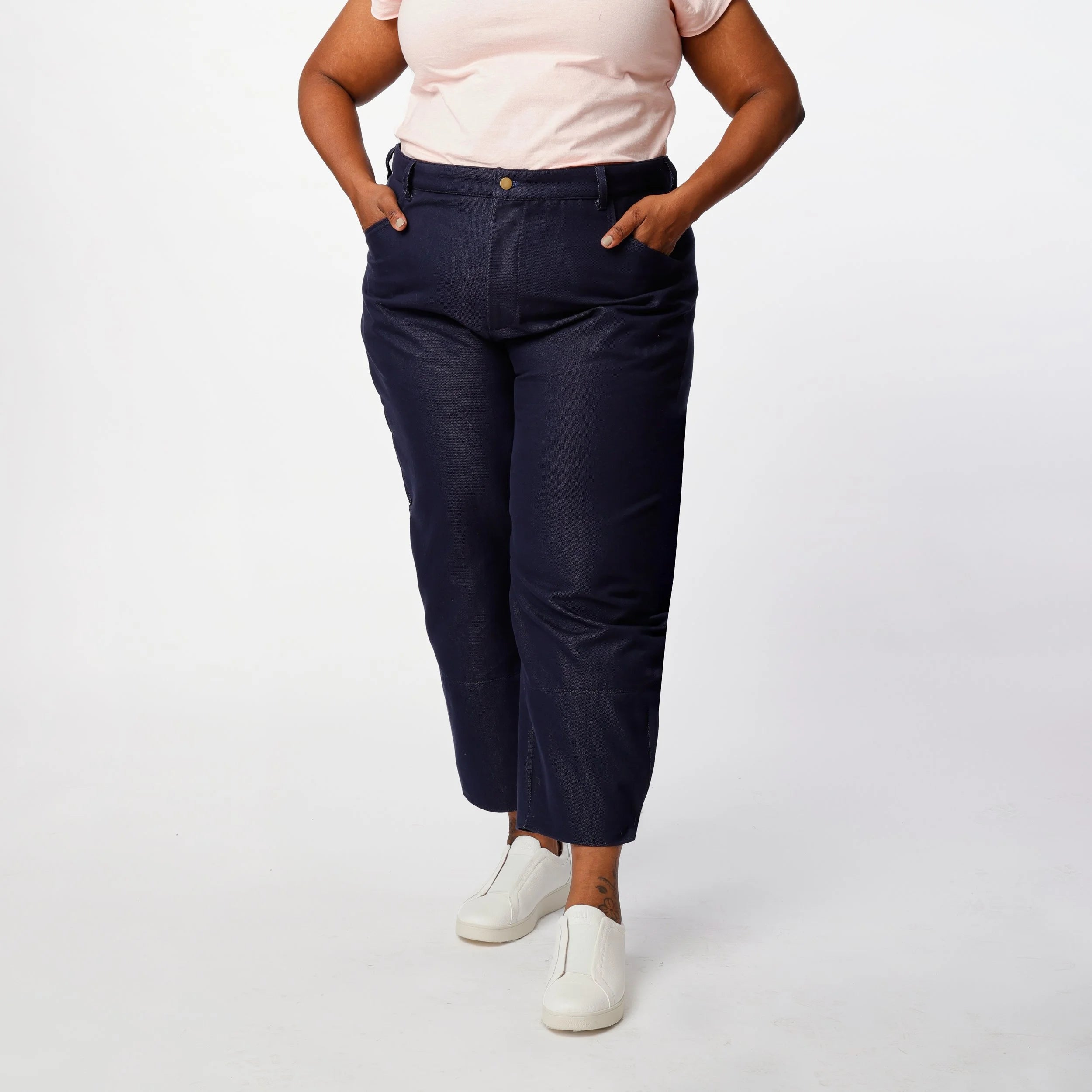 Shop Pant sewing pattern — plus size model wearing high-waisted barrel leg pant in indigo denim twill with front pockets and belt, front close view