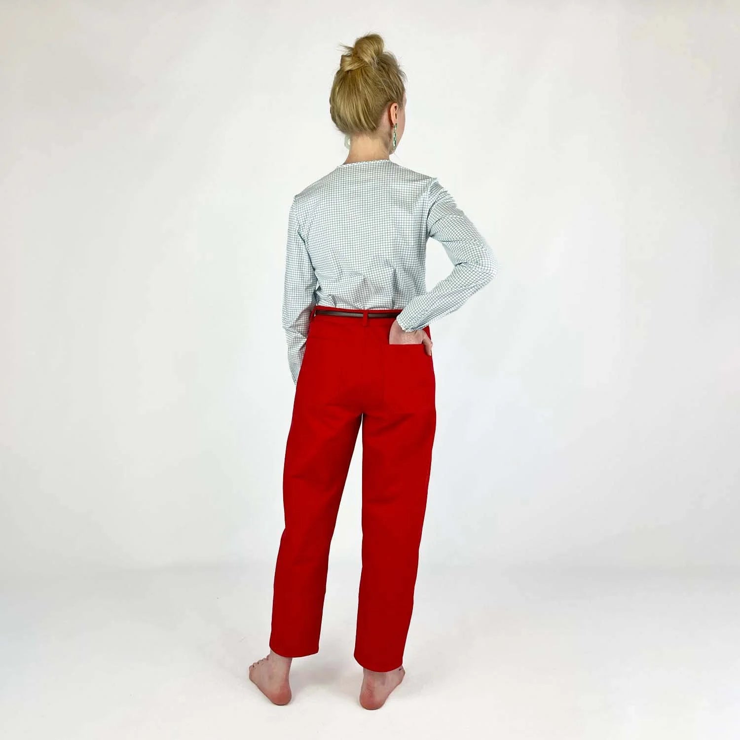 Shop Pant sewing pattern — model wearing high-waisted barrel leg pant in red herringbone twill with front pockets and belt, back view