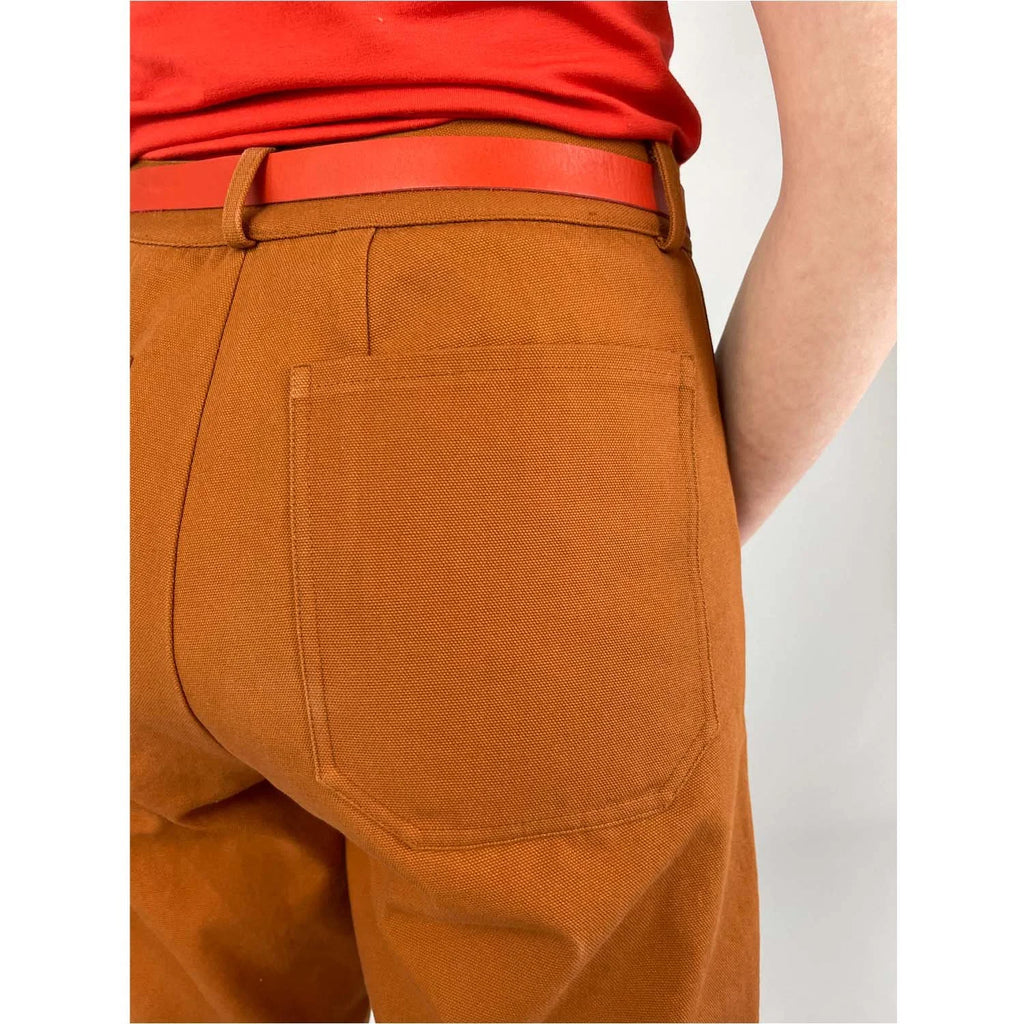 Shop Pant sewing pattern — model wearing high-waisted barrel leg pant in rust brown twill with front pockets and belt, back pocket view