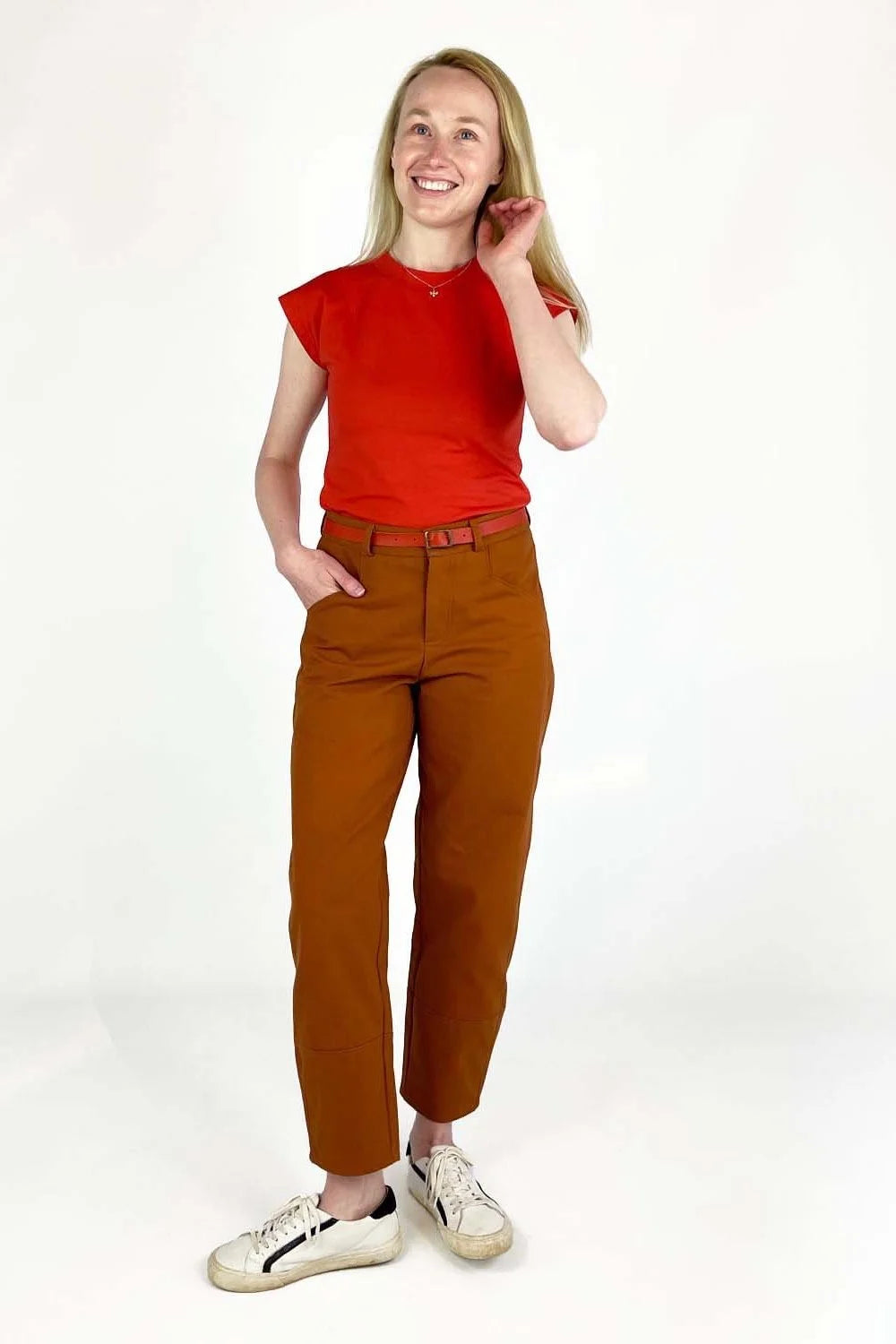 Shop Pant sewing pattern — model wearing high-waisted barrel leg pant in rust brown twill with front pockets and belt, front view