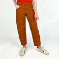 Shop Pant sewing pattern — model wearing high-waisted barrel leg pant in rust brown twill with front pockets and belt, close front view