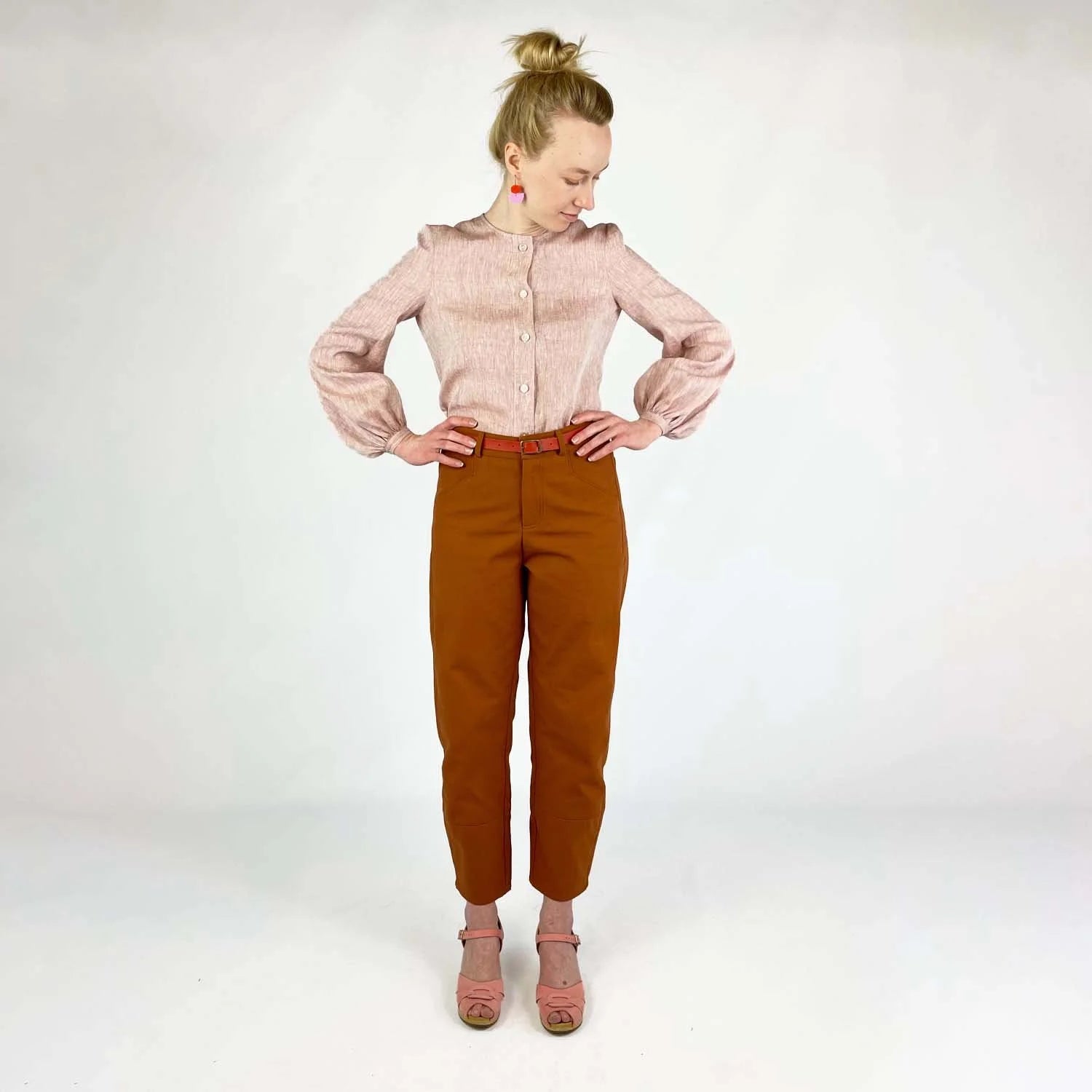 Shop Pant sewing pattern — model wearing high-waisted barrel leg pant in rust brown twill with front pockets and belt, rose shirt front view