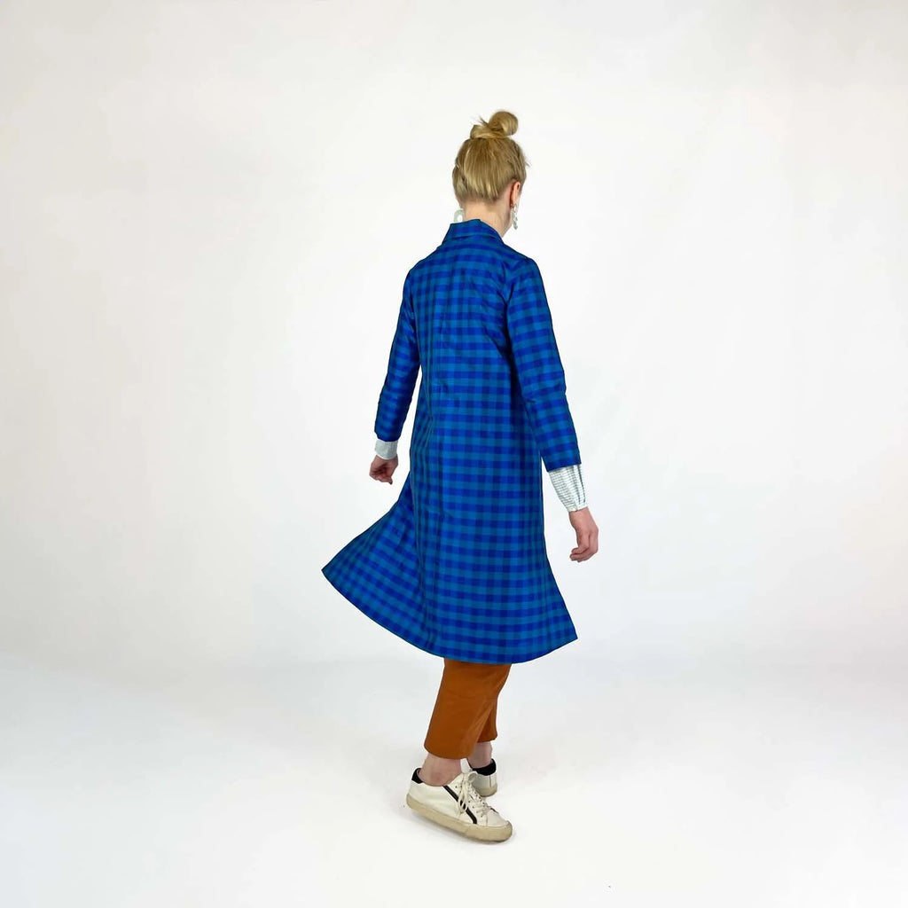 Swing Coat sewing pattern — model wearing an A-line swing coat in blue gingham with notched lapel, three-quarter sleeves, and gold buttons, back view