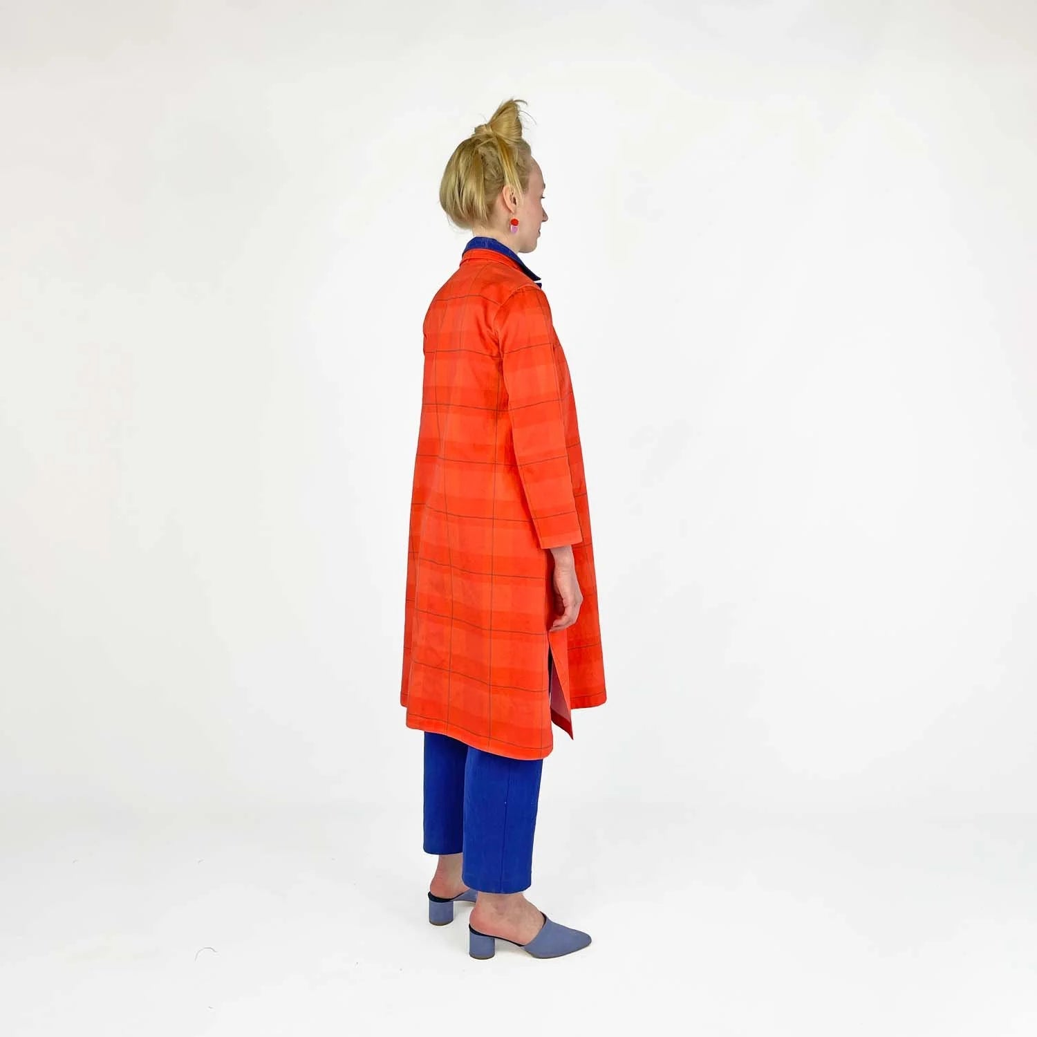Swing Coat sewing pattern — model wearing an A-line swing coat in bold orange plaid with notched lapel, three-quarter sleeves, and gold buttons, side view