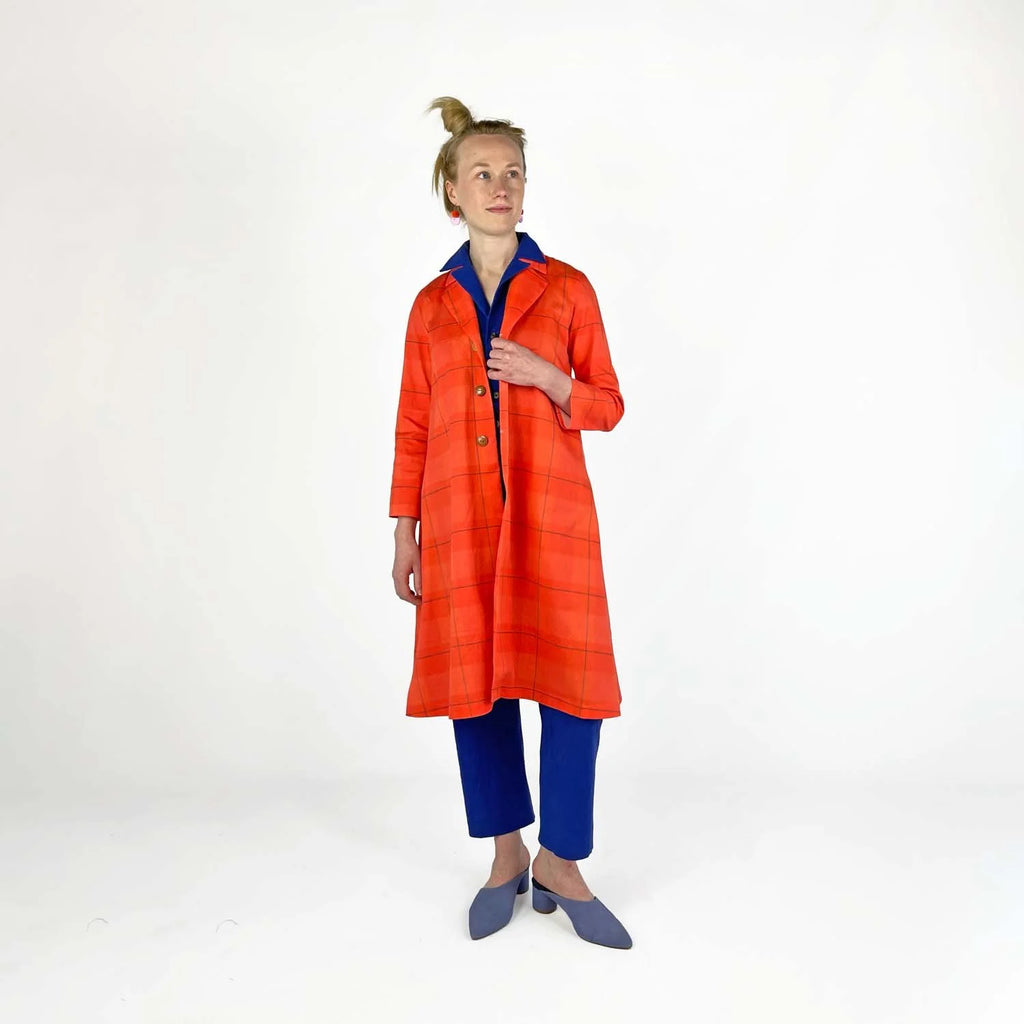 Swing Coat sewing pattern — model wearing an A-line swing coat in bold orange plaid with notched lapel, three-quarter sleeves, and gold buttons, open view